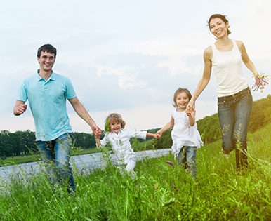 A family walking on a grassy hill while holding hands.
