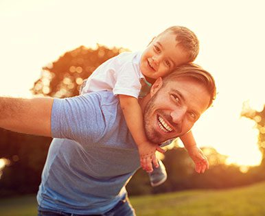 A boy getting a piggy-back ride from his father.