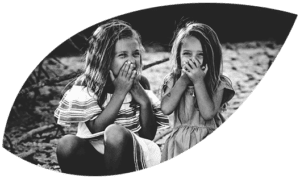 Leaf cutout of two girls giggling.