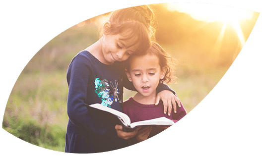 WishList Two girls reading a book at sunset.